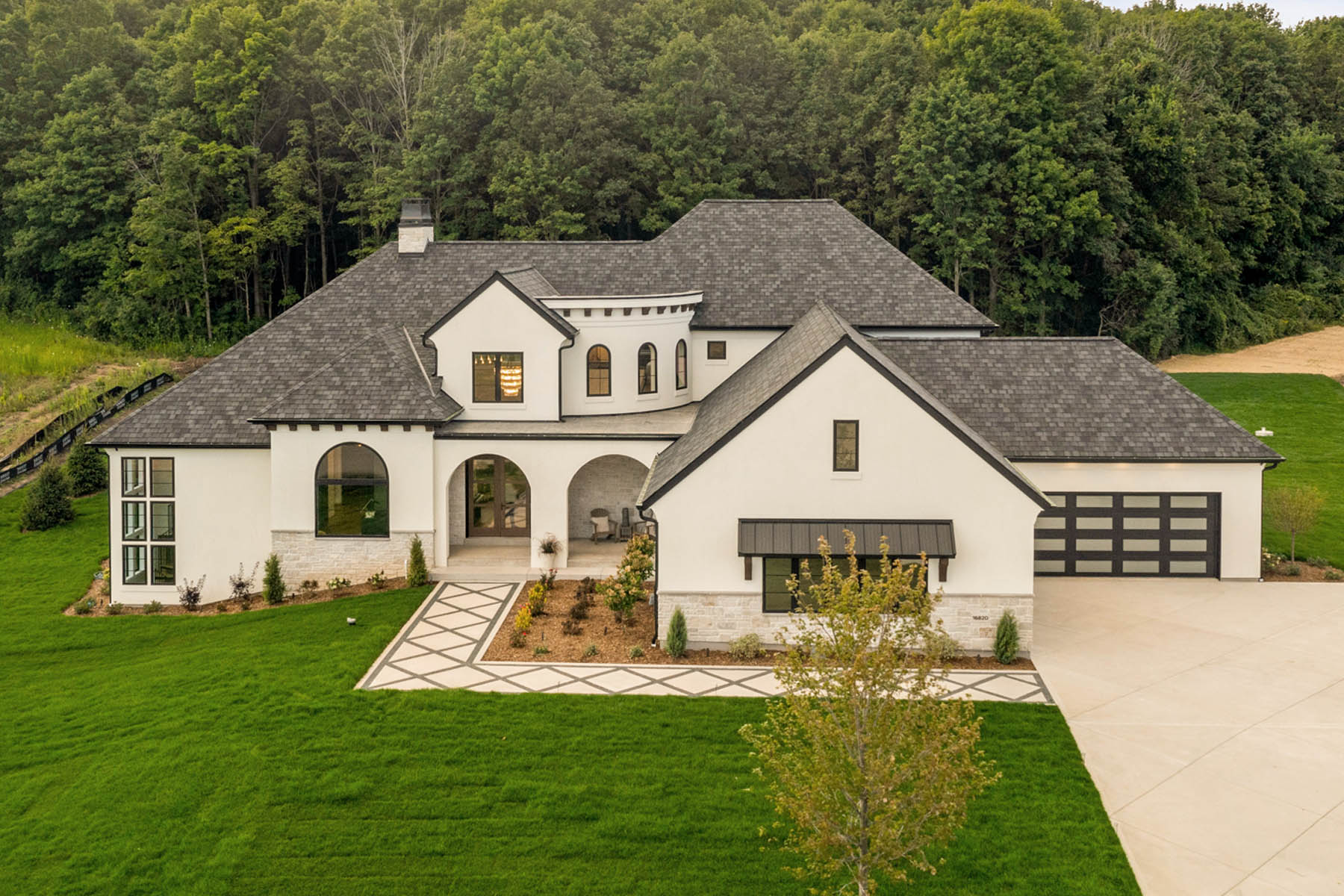 Mediterranean style home with landscaping, black framed windows, arches and parapet