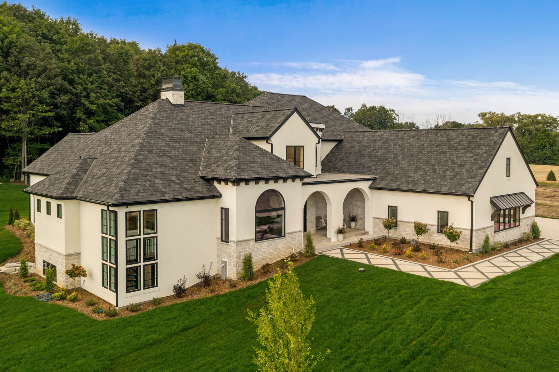 Mediterranean style home with landscaping, black framed windows, arches and parapet